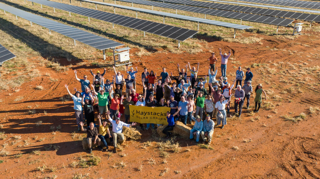 A drone image of a group of people at Haystacks solar farm in front of some solar panels